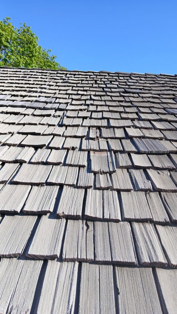 Cracked and deteriorating cedar shake roofing in need of repair